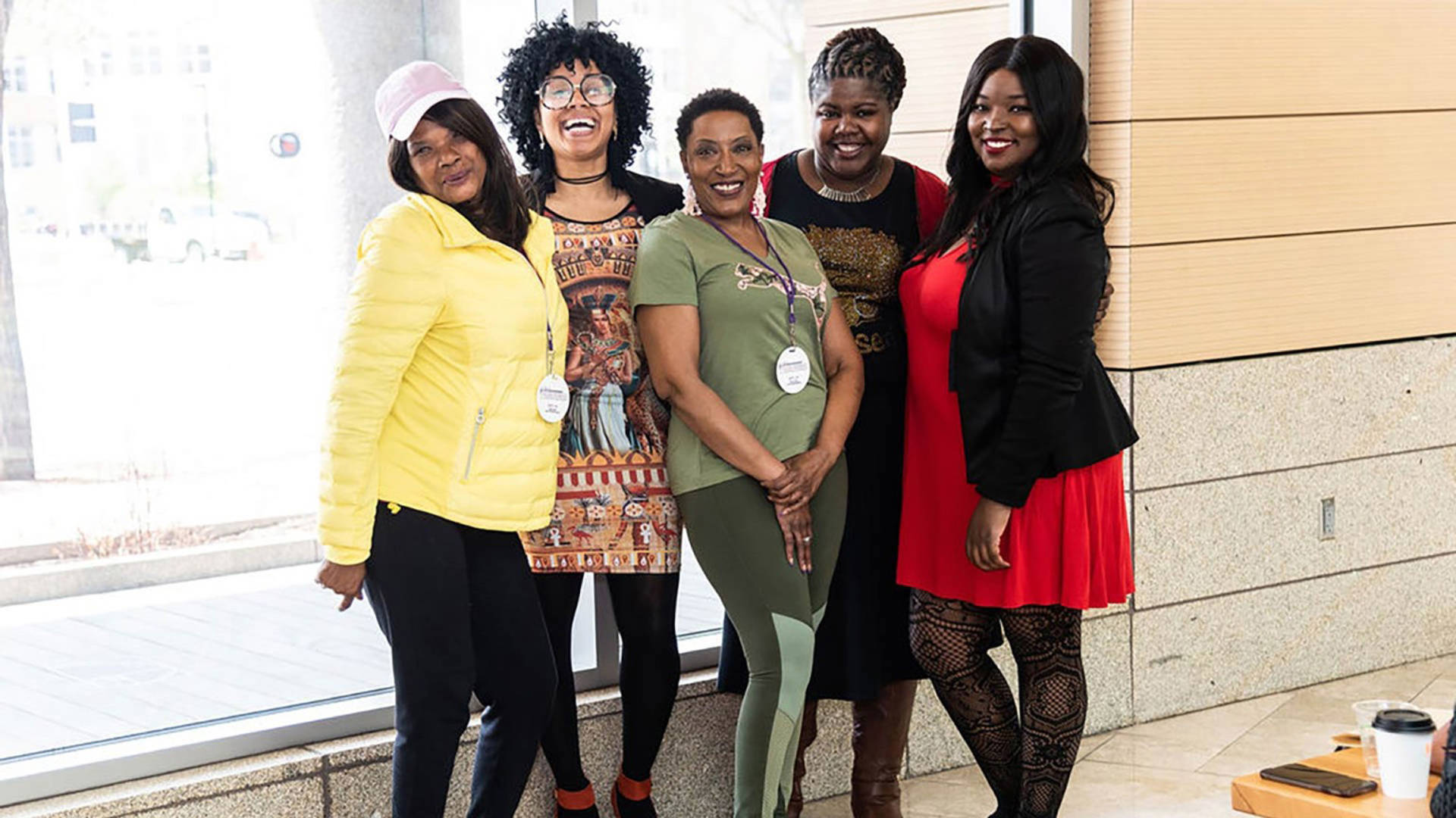 Five african american women standing together for a photo and smiling.