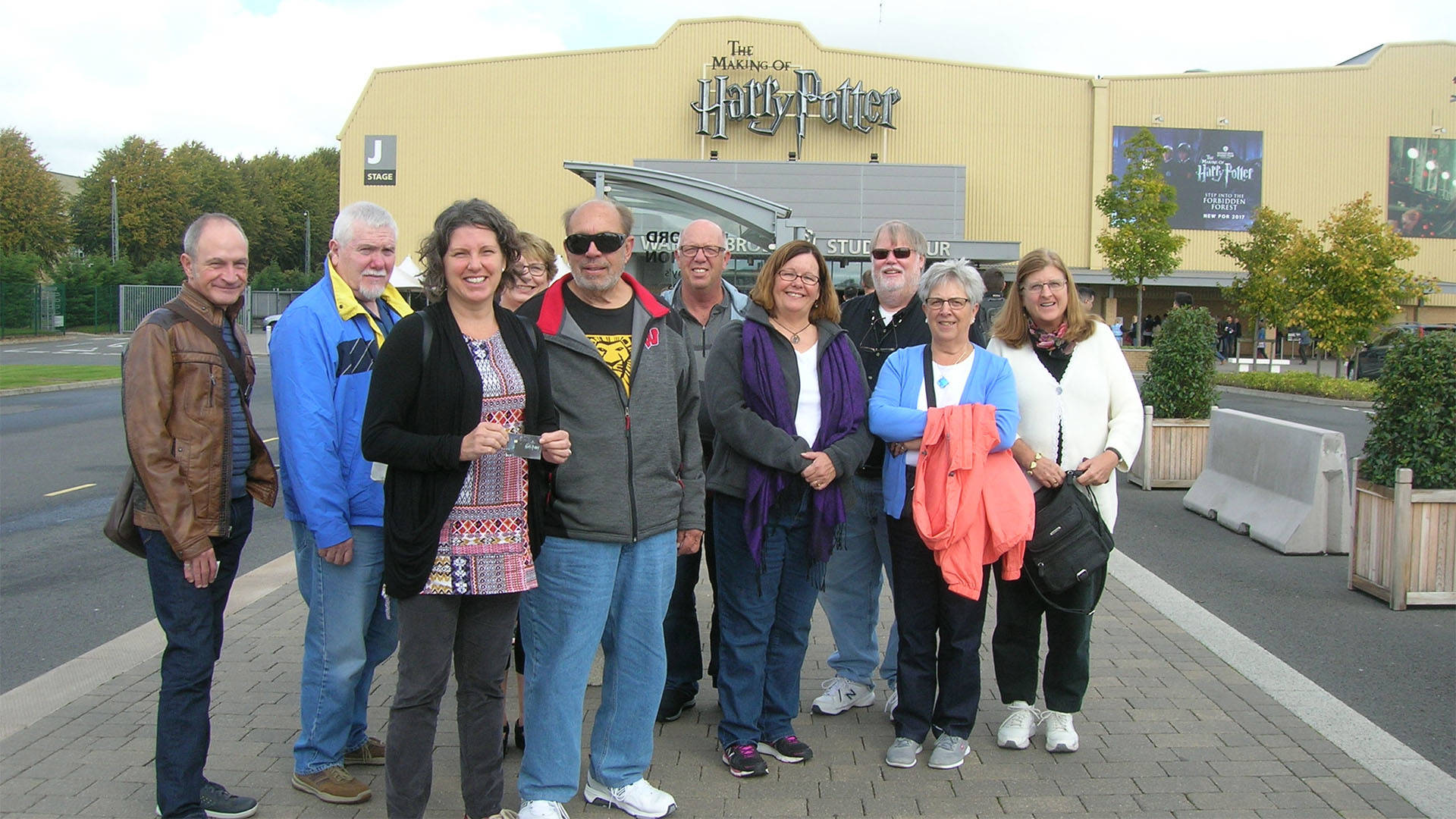 A group of older caucasian adults standing together in front of a building labeled "The Making of Harry Potter"