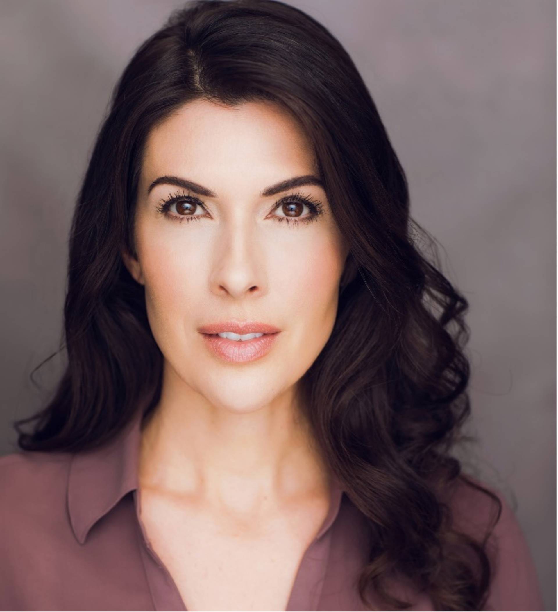 Headshot of a young woman with medium complexion, long dark hair and brown eyes in a plum colored top with collars.