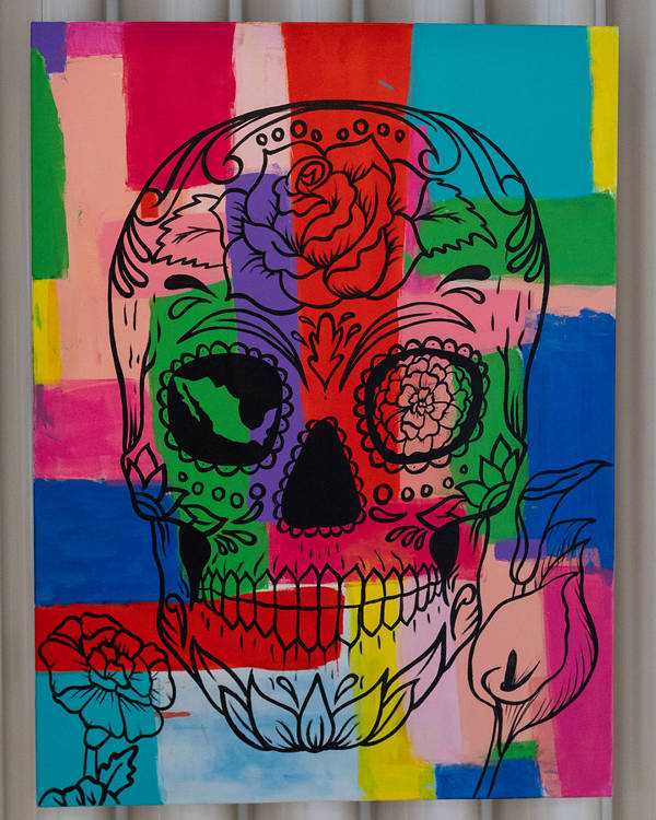 A colorful painting portraying a skull and flowers.