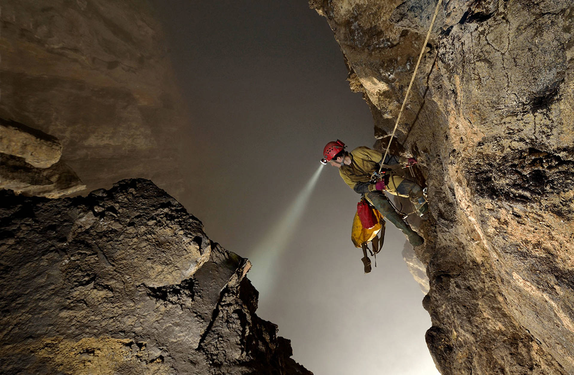 A climber hanging from a rope in a giant cave