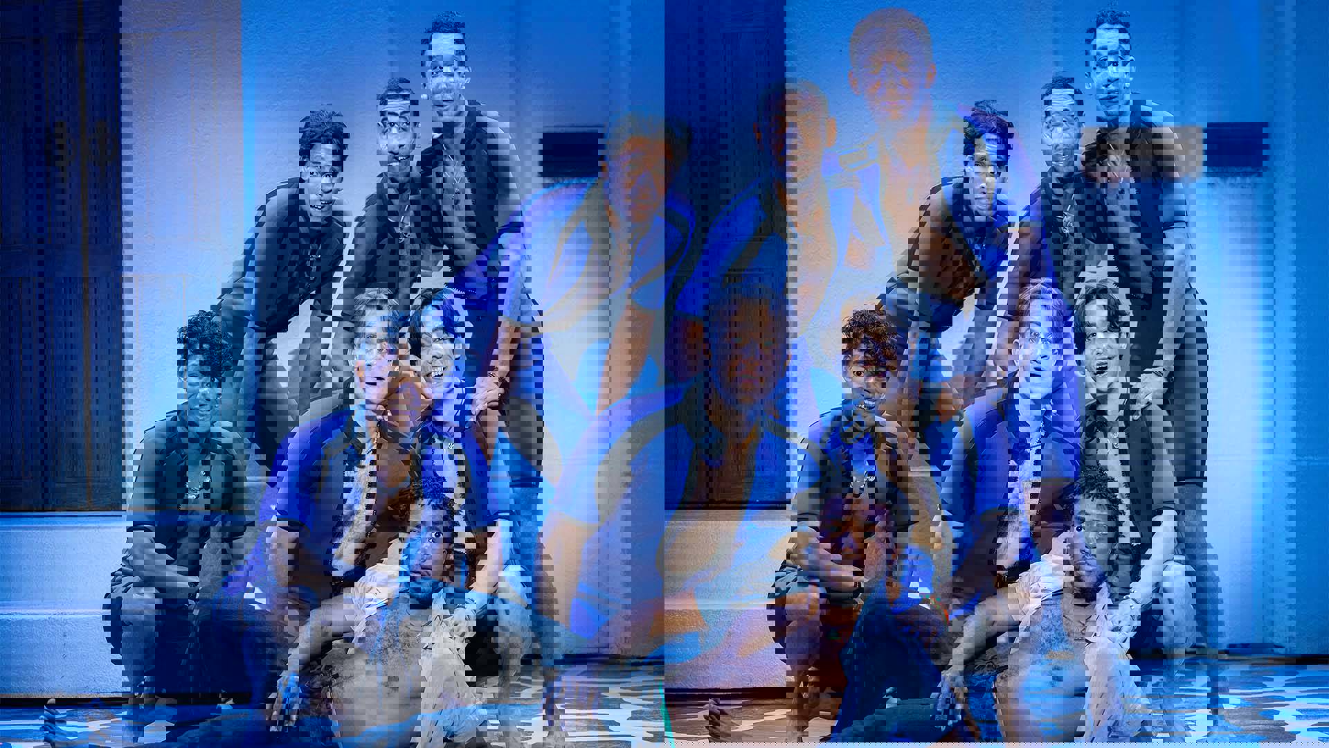 A group of young men, mostly in matching speedo suits, grouped together and facing the viewer.