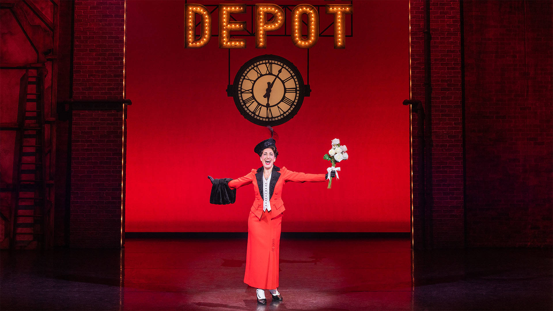 A light complexion woman with dark hair in a red dress holding a bouquet of flowers under a clock and a sign that reads "cleveland union depot."