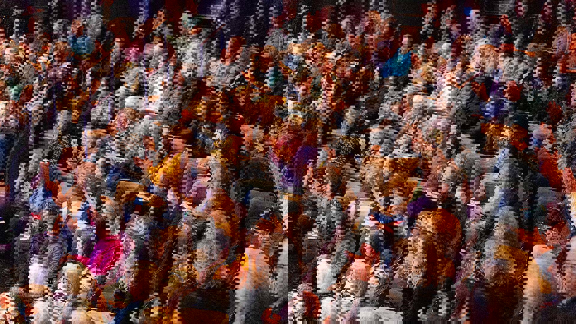 An audience viewed from the side applauding.