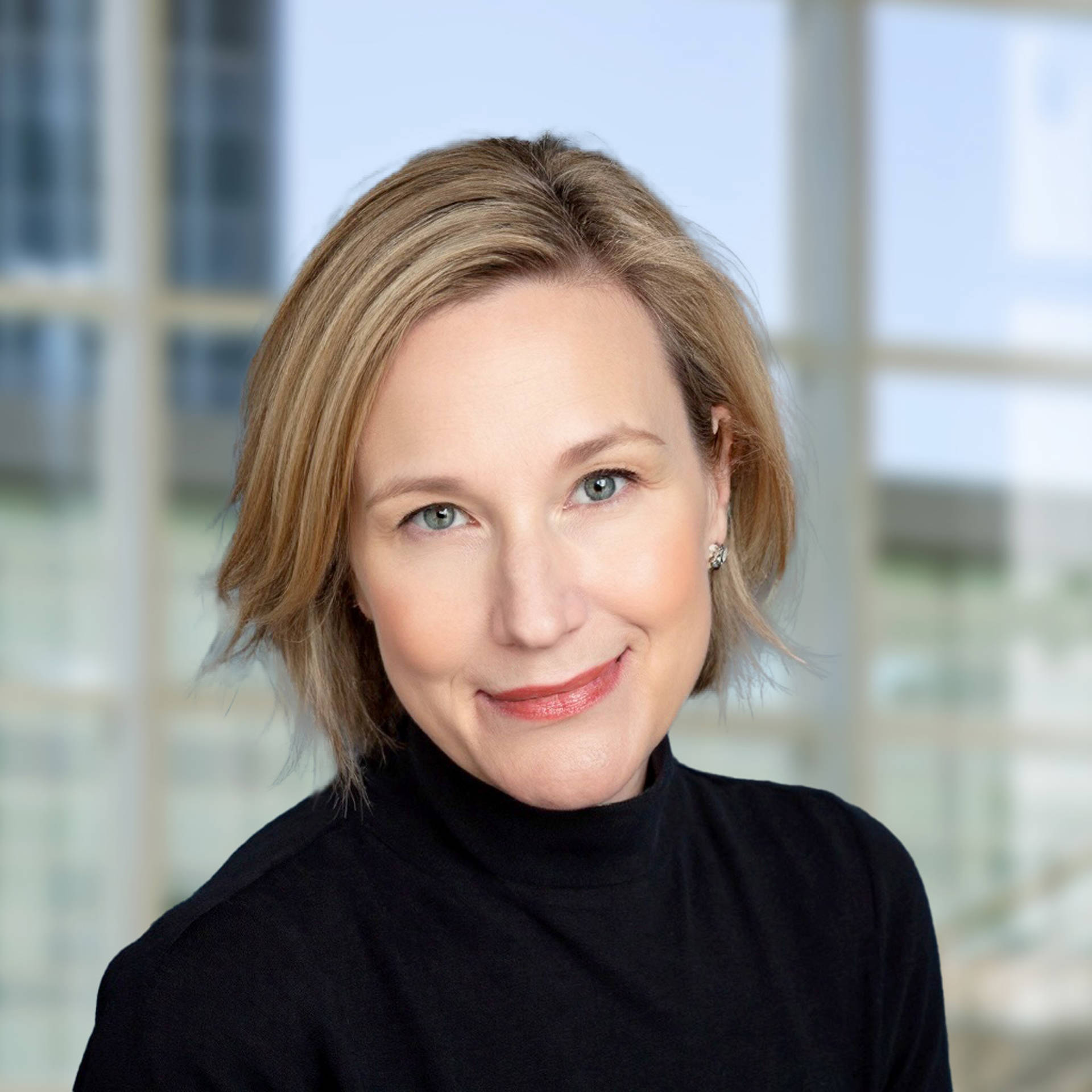 Headshot of Jenie Dahlmann. She is a white woman with short, blonde hair and light, hazel eyes. She is wearing a dark jacket over a blue shirt.