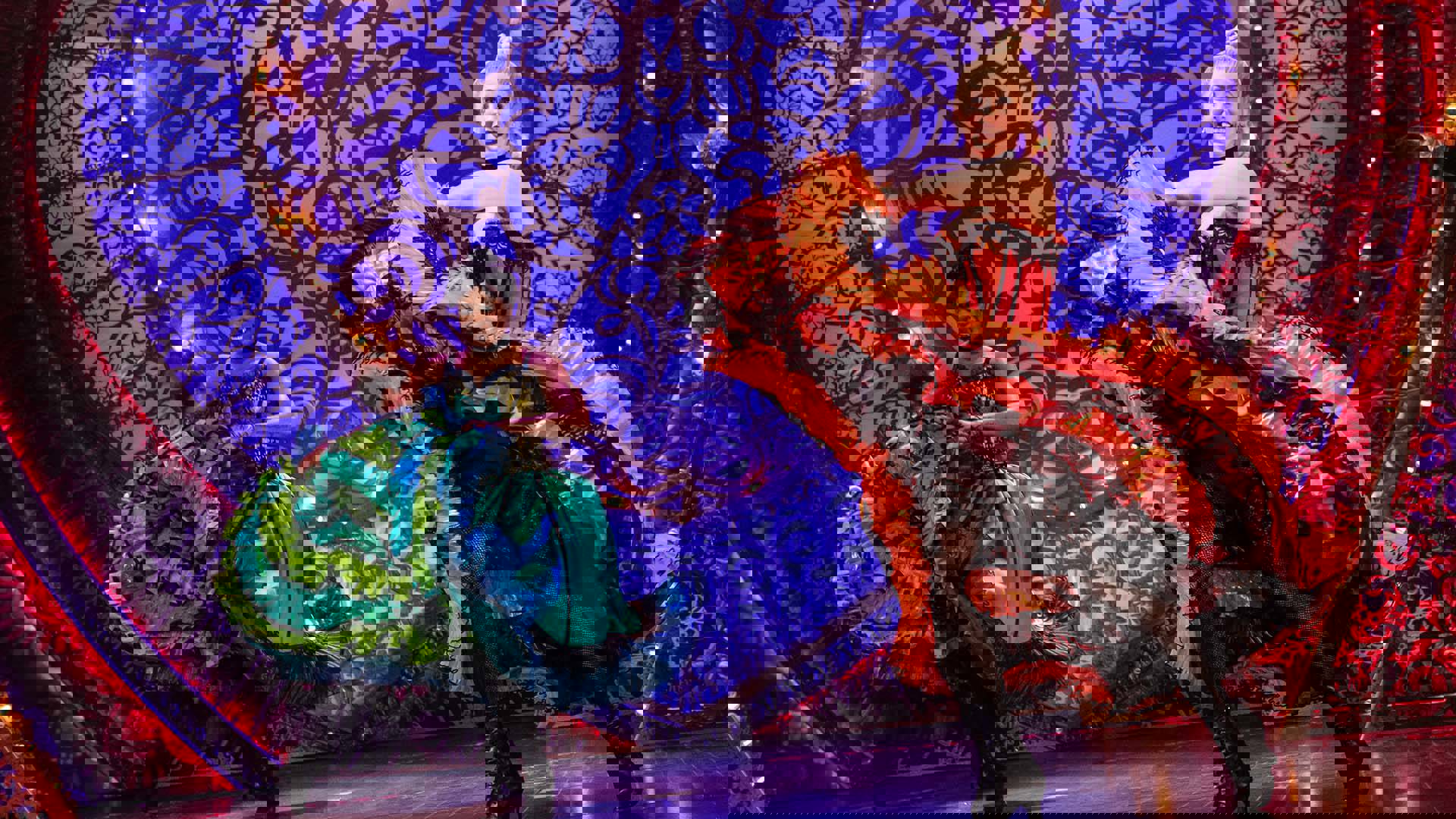 Two women in colorful dresses dancing and throwing their skirts around.