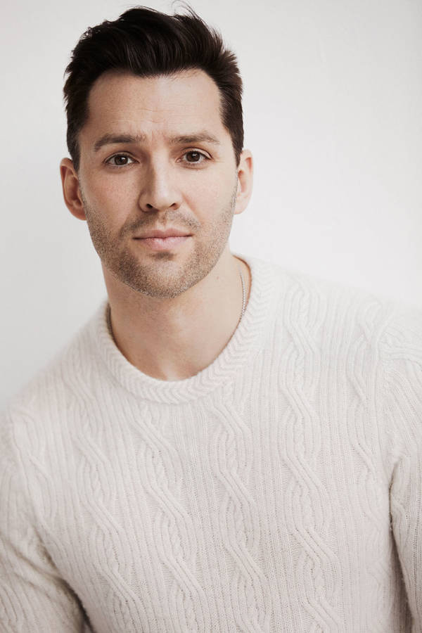 Headshot of Ryan Silverman. He has a handsome youthful face with short brown hair and brown eyes. He is wearing a white sweater.