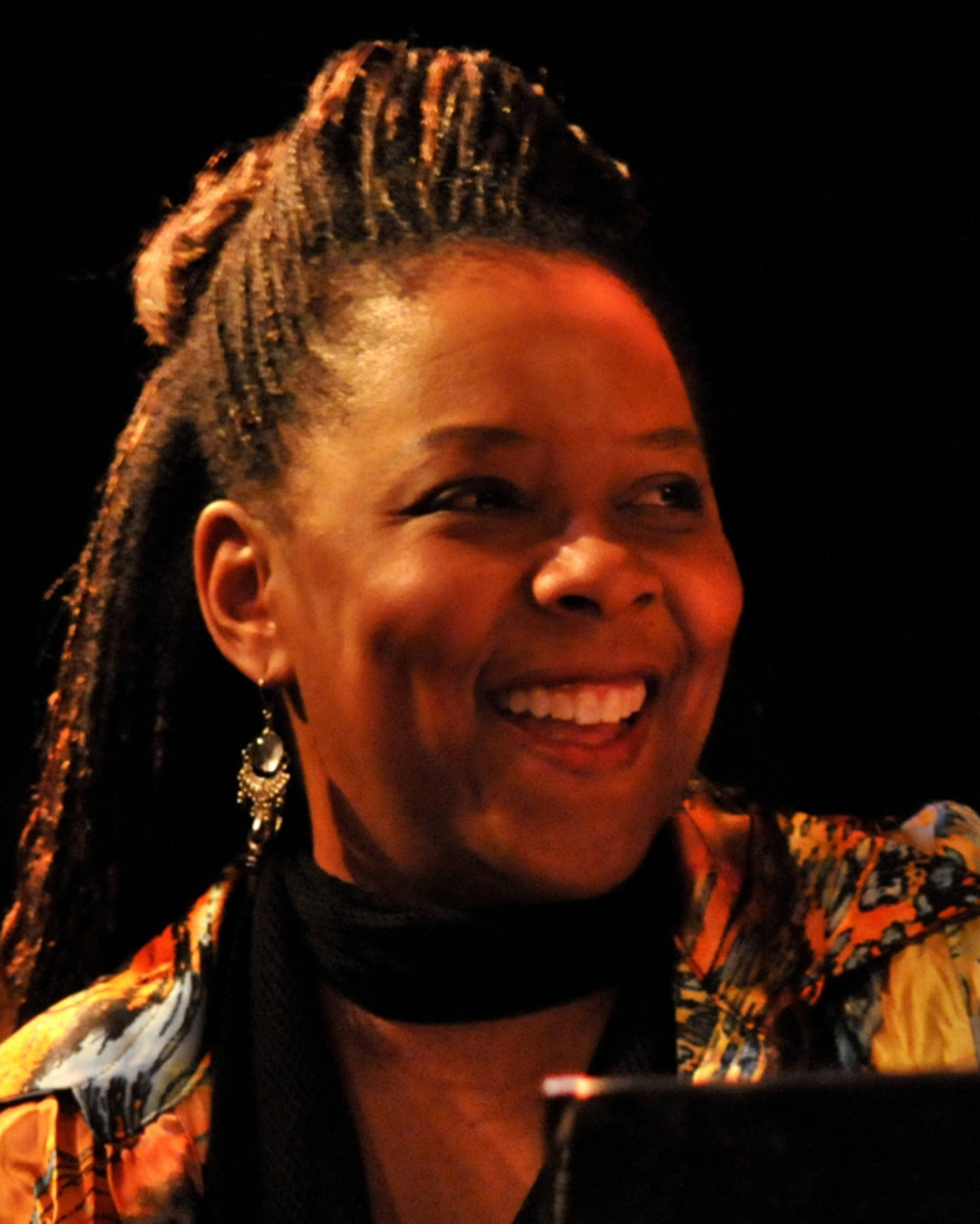 Headshot of a smiling african american woman with dark hair and a colorful top.