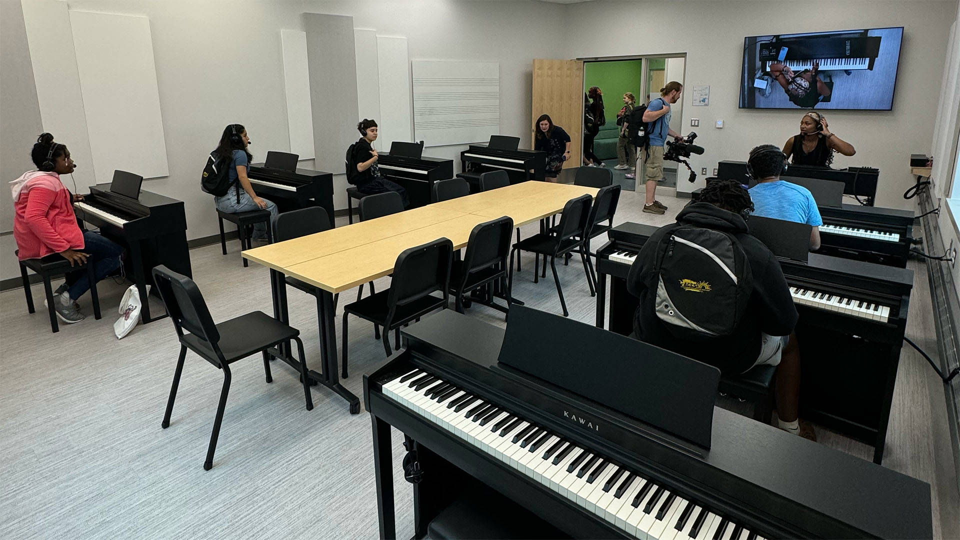 students sitting at individual electric pianos in a classroom.
