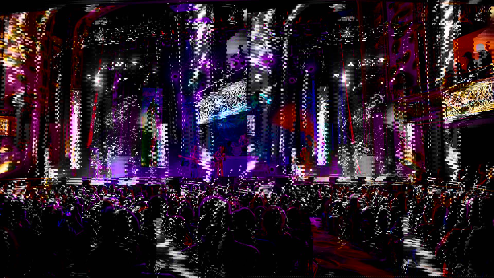 Four Beatles impersonators performing in front of a full house