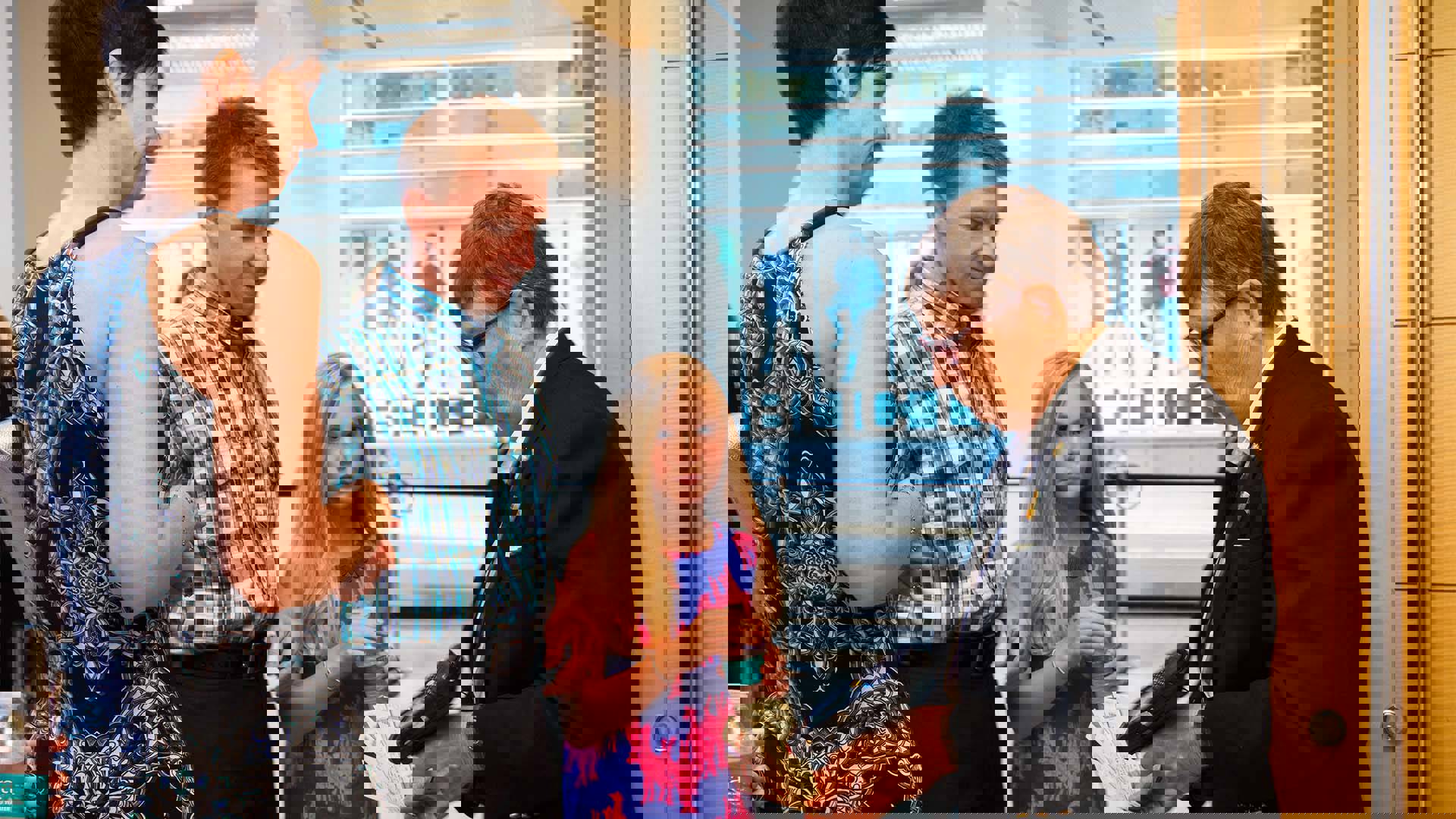 A man woman and child get their tickets scanned by a middle aged woman in a dark suit and glasses.