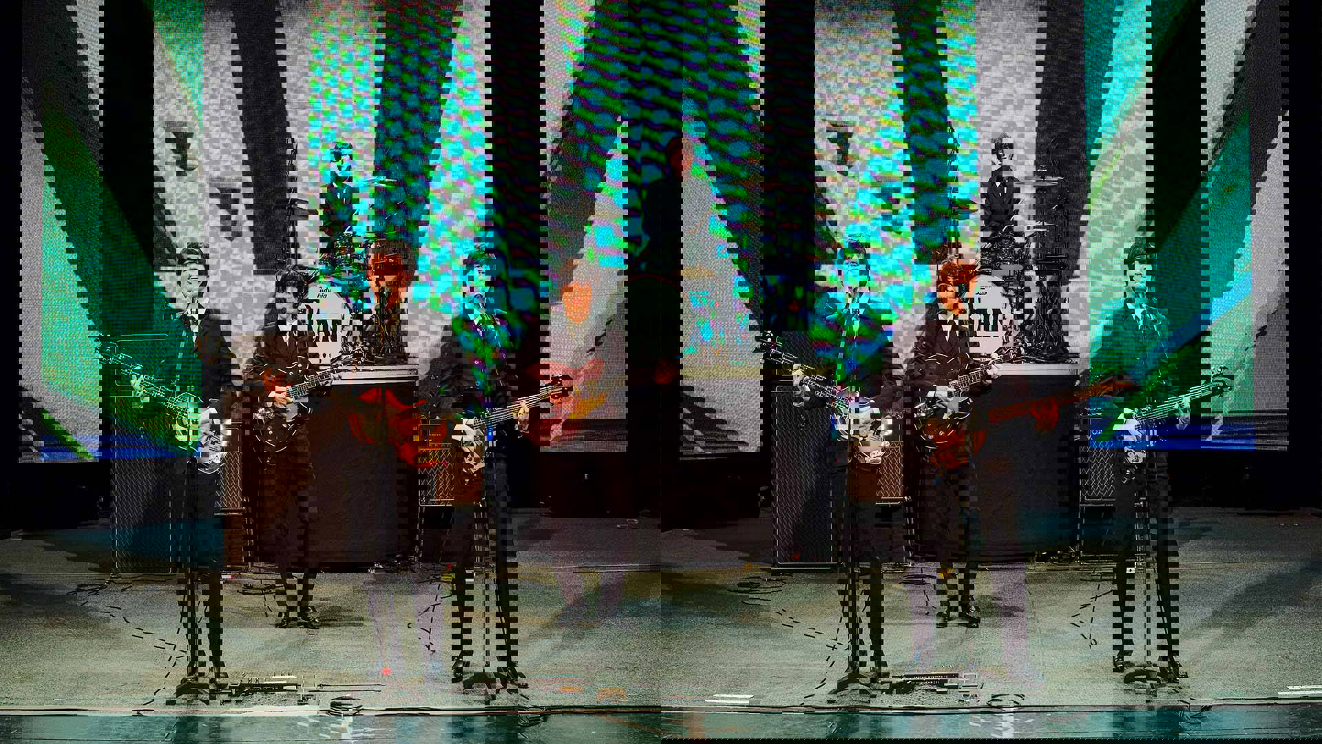 Four Beatles impersonators performing the Ed Sullivan show - wearing black suits with ties