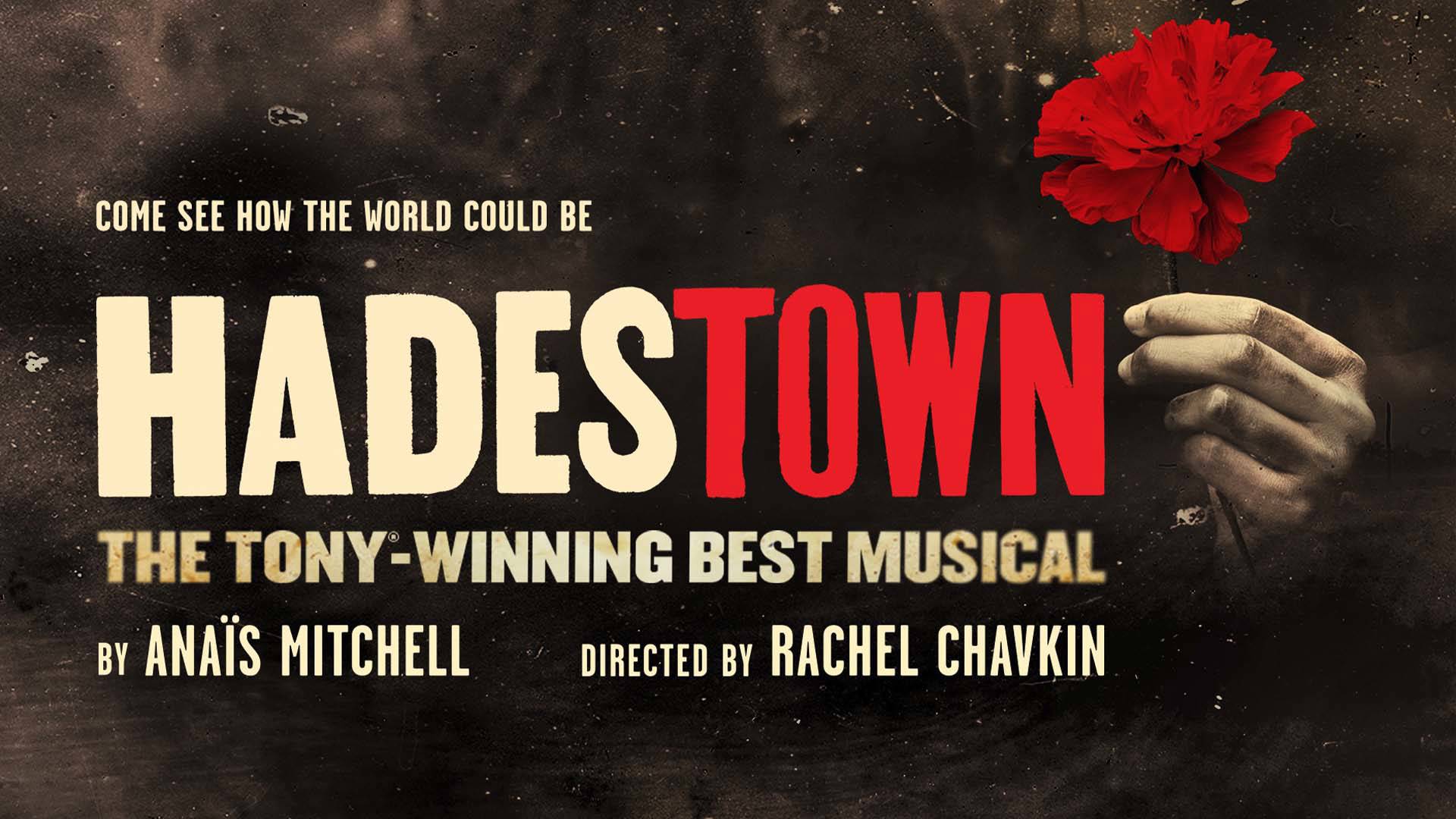 Come see how the world could be: Hadestown - The Tony-Winning Best Musical. A hand holding out a red flower against a dark background..
