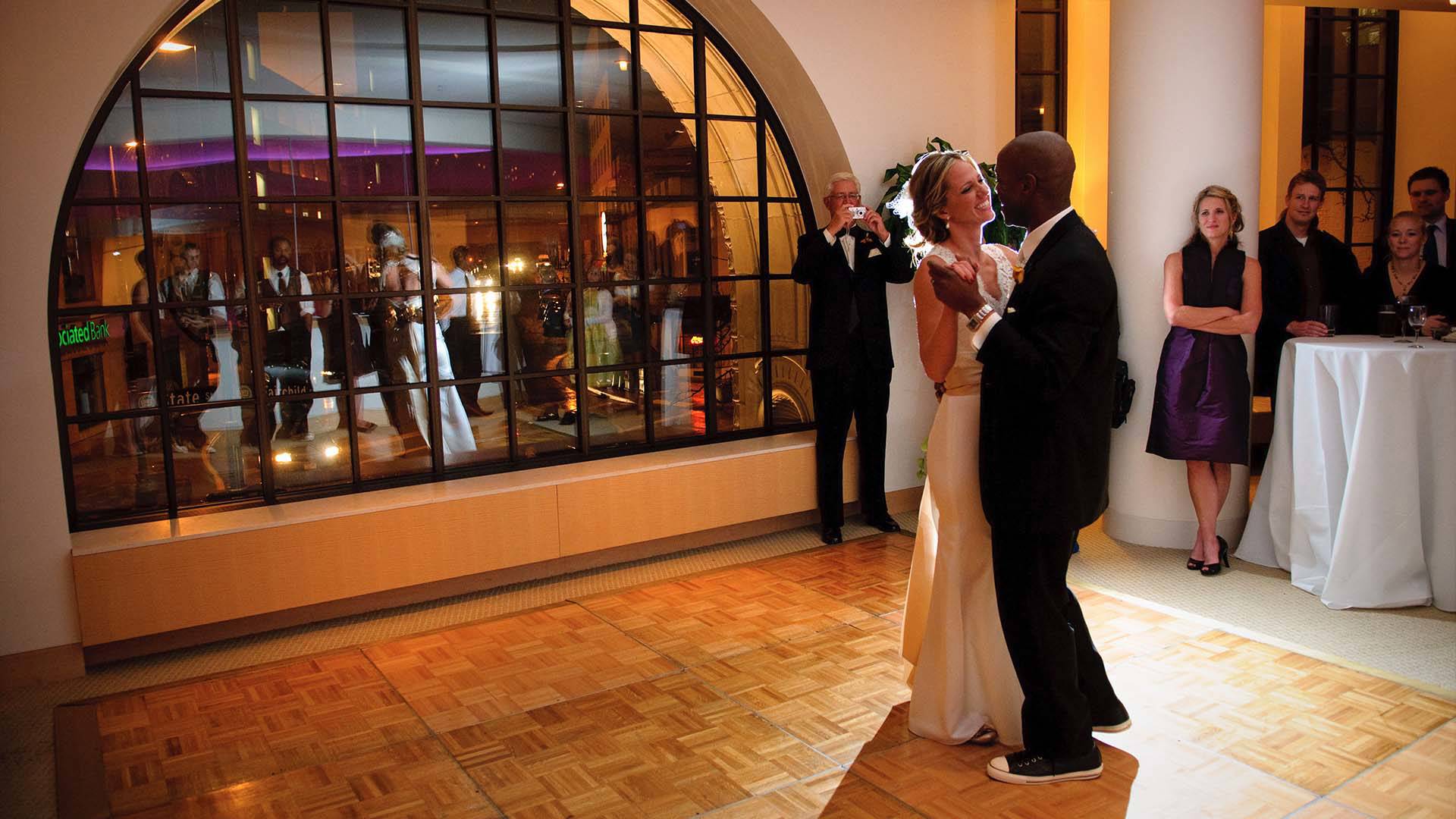 A bride and groom dancing on a dance floor. People watch.