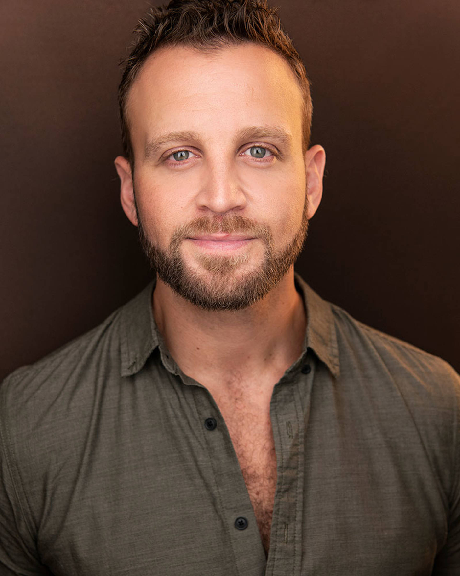 Headshot of a white man with a brown beard, short hair and blue eyes