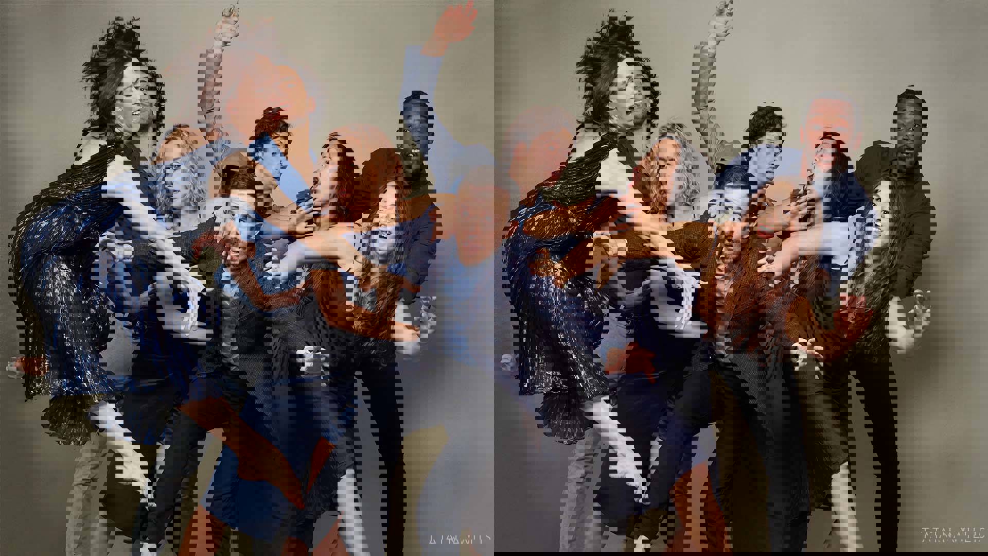 A chaotic image of 8 dancers tangled up and jockying for position in a fun manner. They are all wearing various dark blue outfits