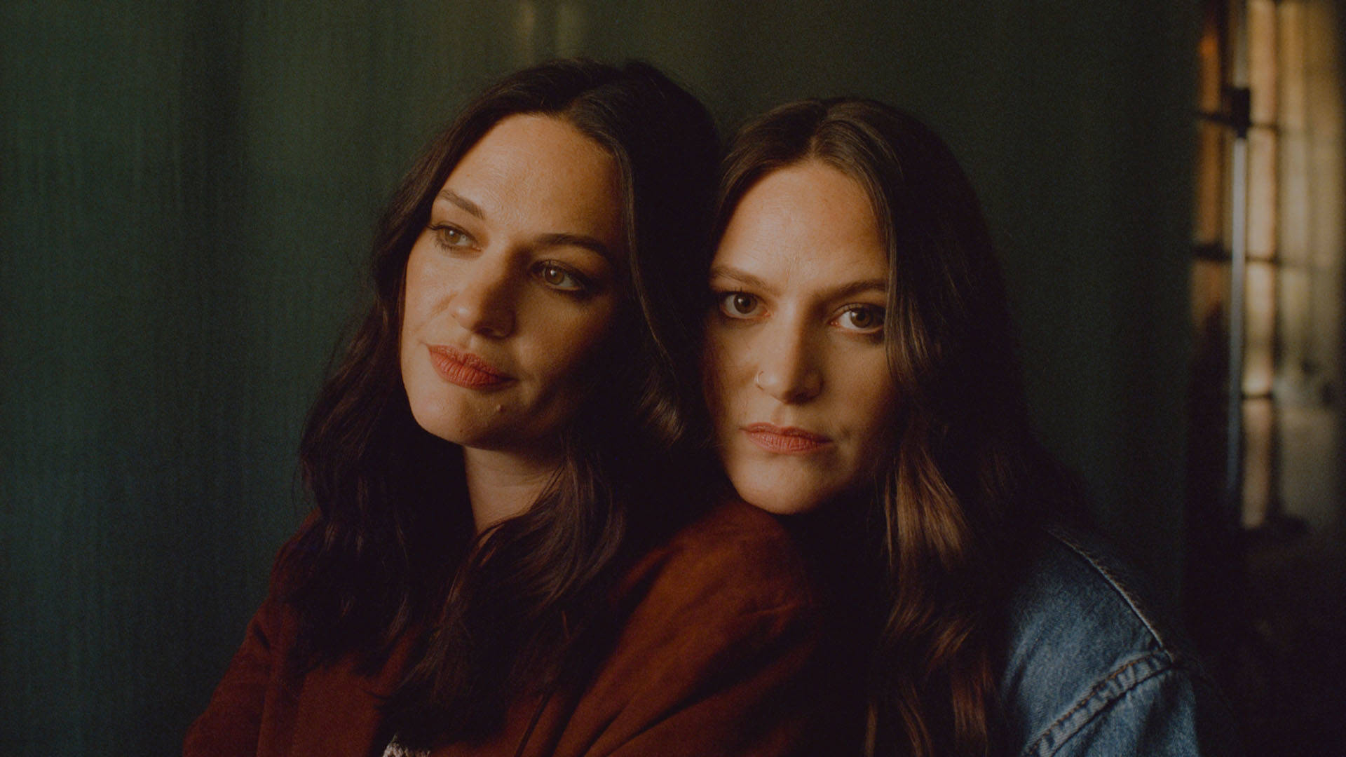 Two young caucasian women with brown hair and brown eyes close together for a headshot photo.