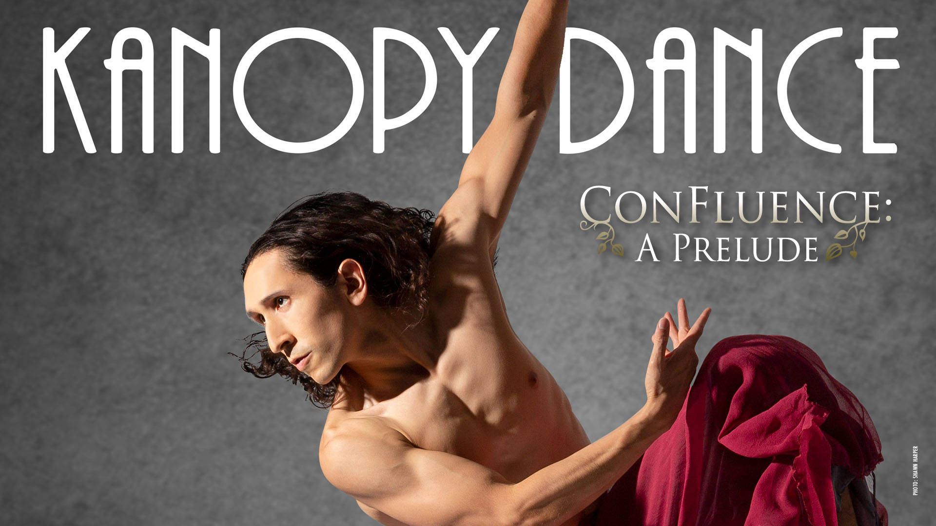 Banner text Reads: "Kanopy Dance Confluence: a Prelude" A fit man with long dark hair and a flowing maroon outfit dances against a grey background