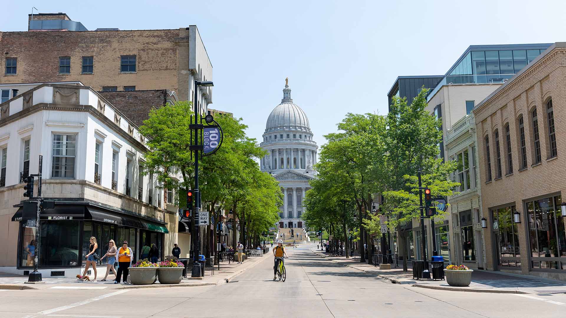 Madison's Capitol viewed from down State St with pedestrians and cyclists in summer
