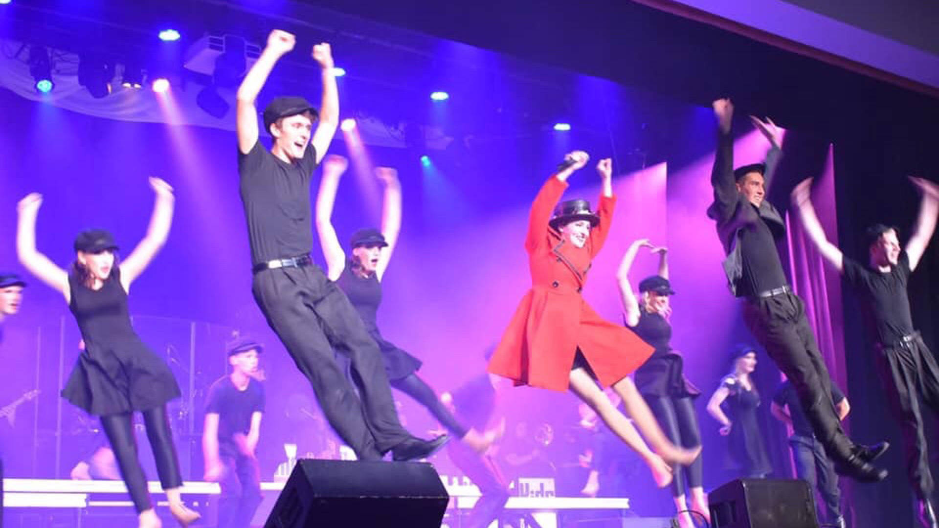 Kids from Wisconsin performing on stage. They are all leaping into the air.