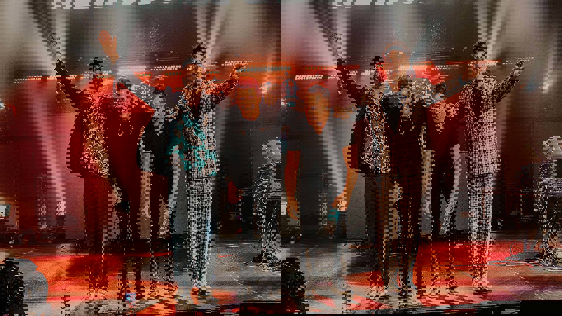 Four smiling men with light complexion bowing at the front of a stage.