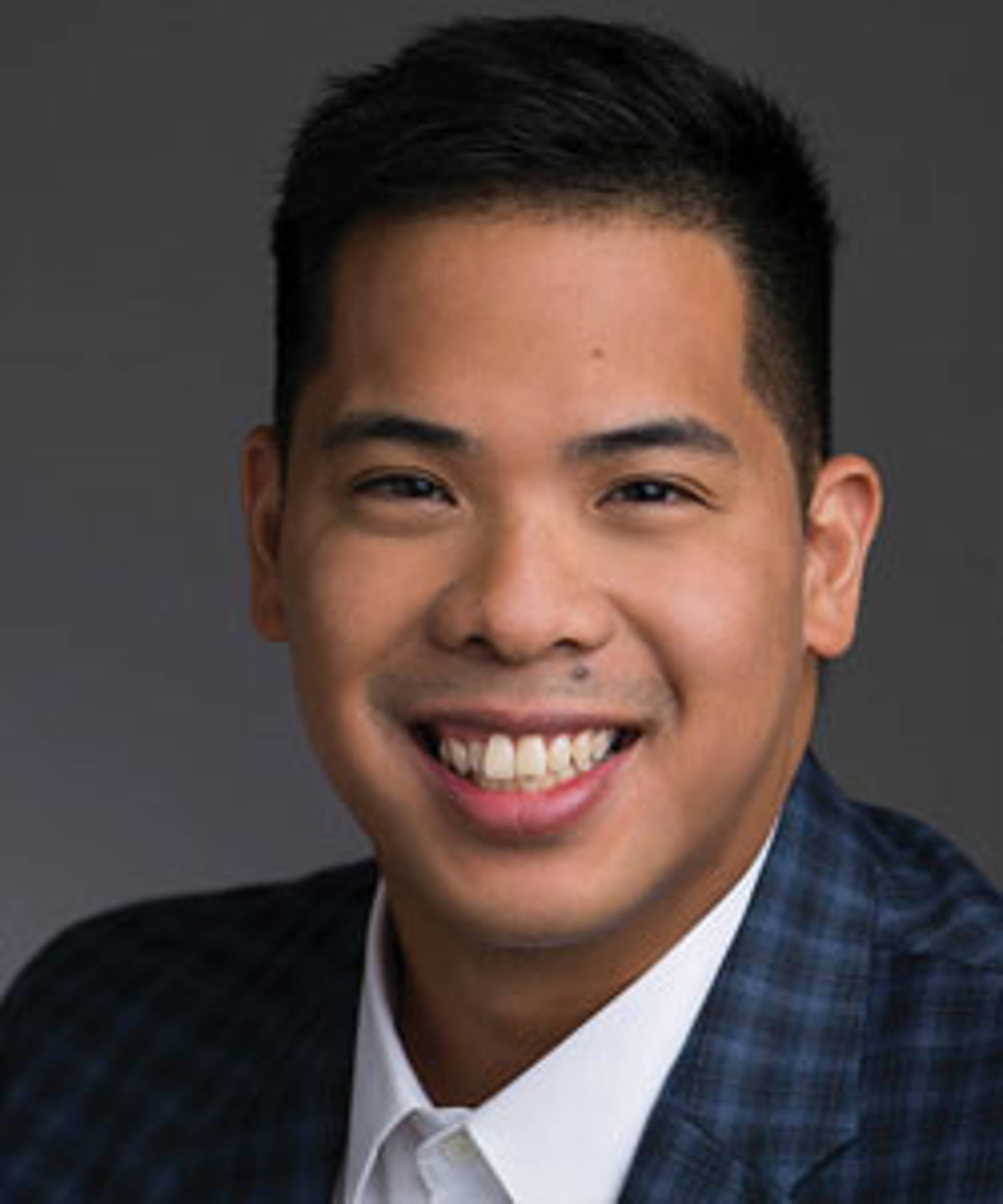 Headshot of a smiling man with brown eyes and short dark hair