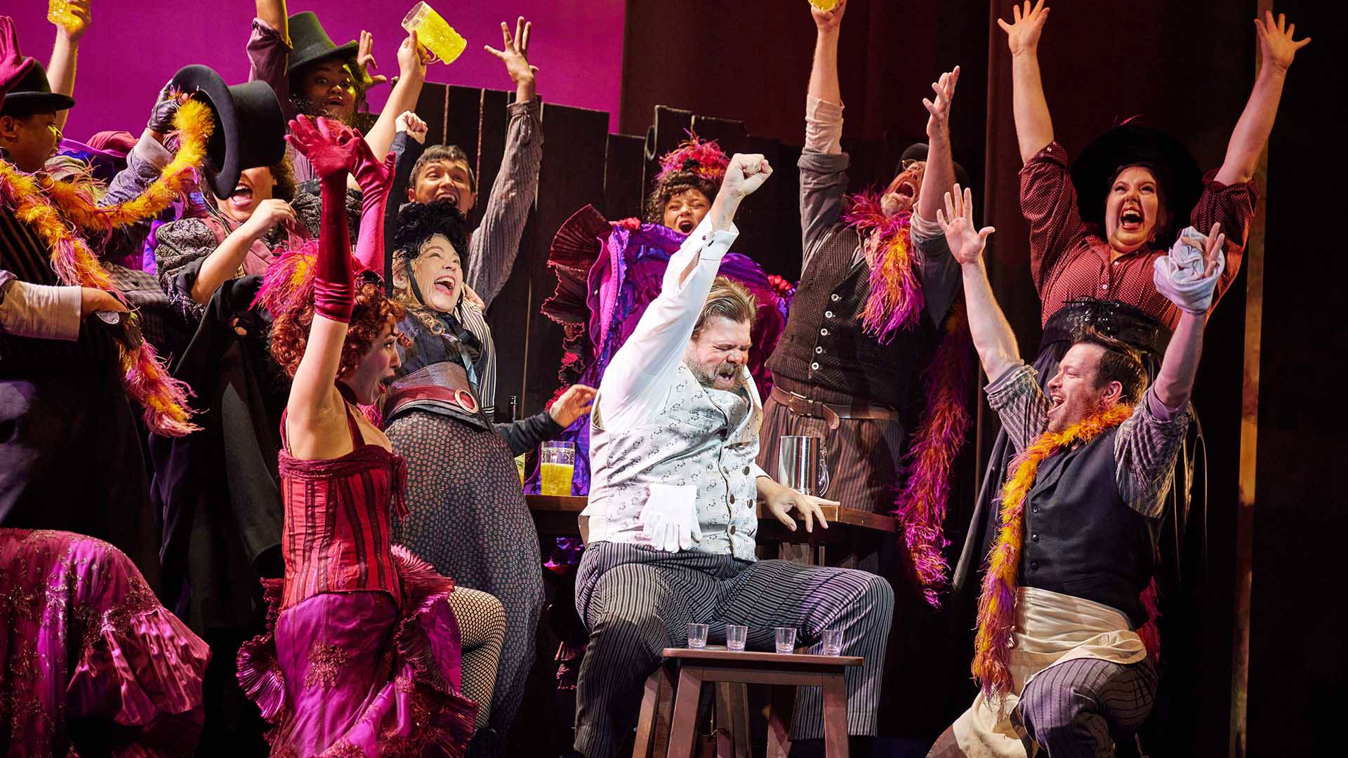 A group of people at a bar cheer with their hands in the air.