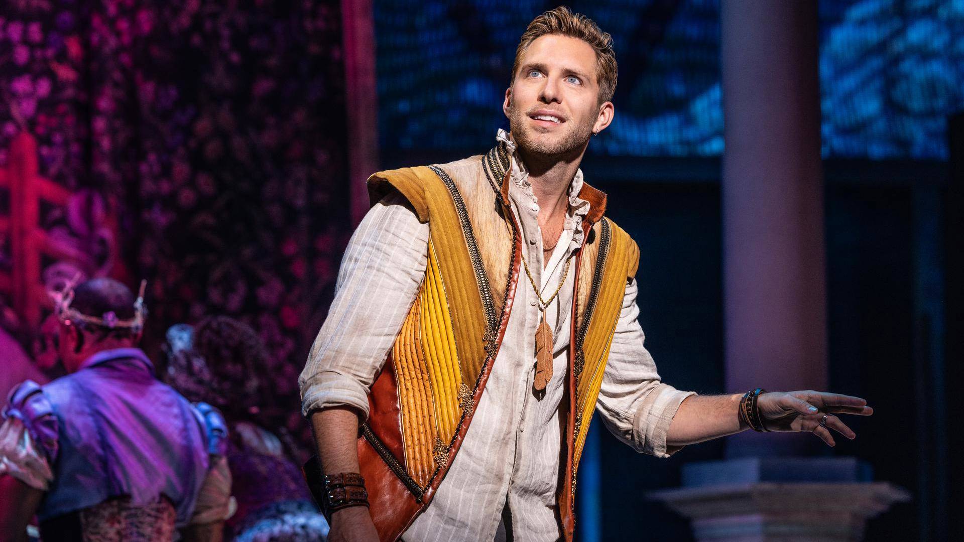 A man with a yellow and brown vest with light complexion and short brown hair.