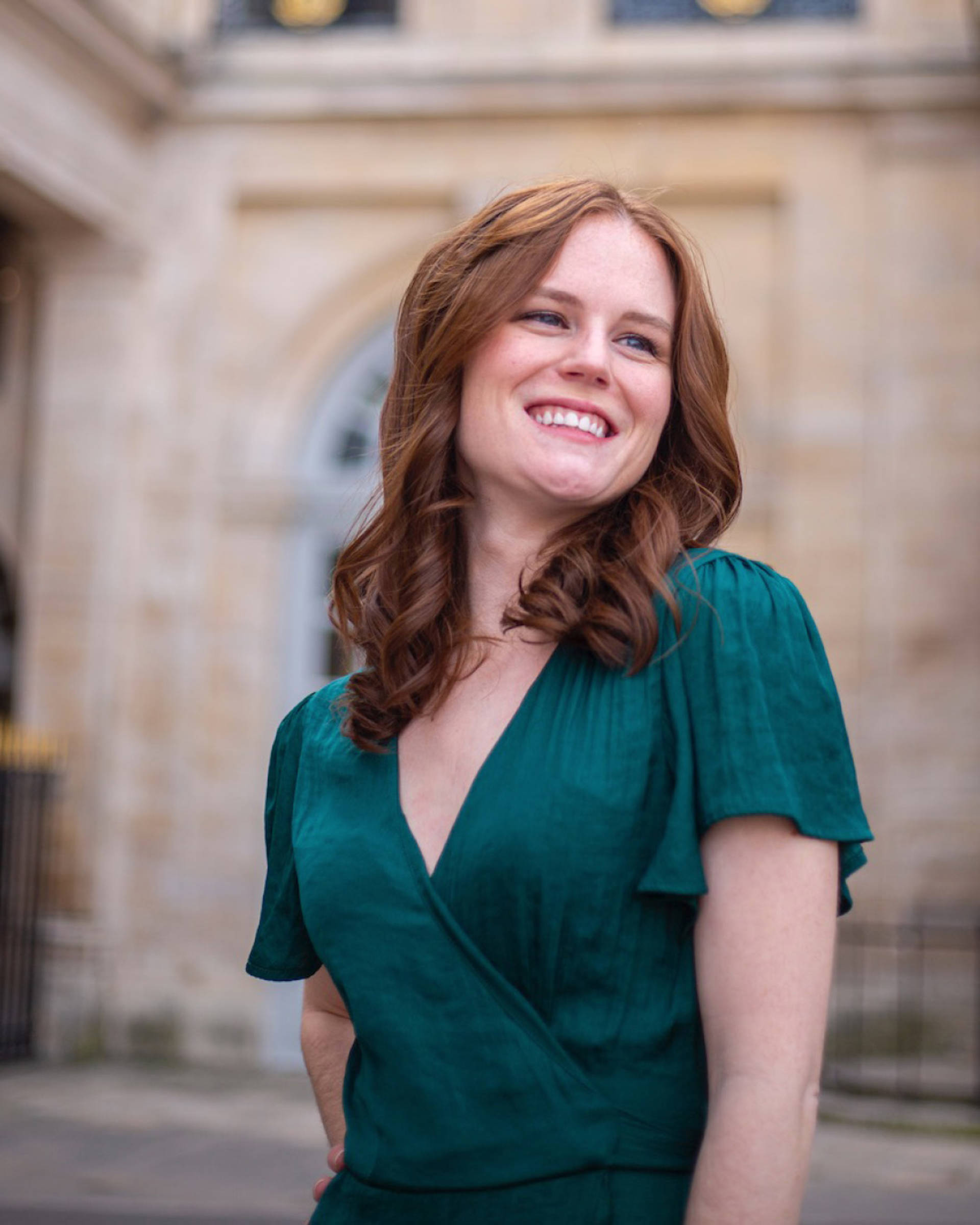 Headshot of a caucasian woman with reddish brown hair, blue eyes and a green top.