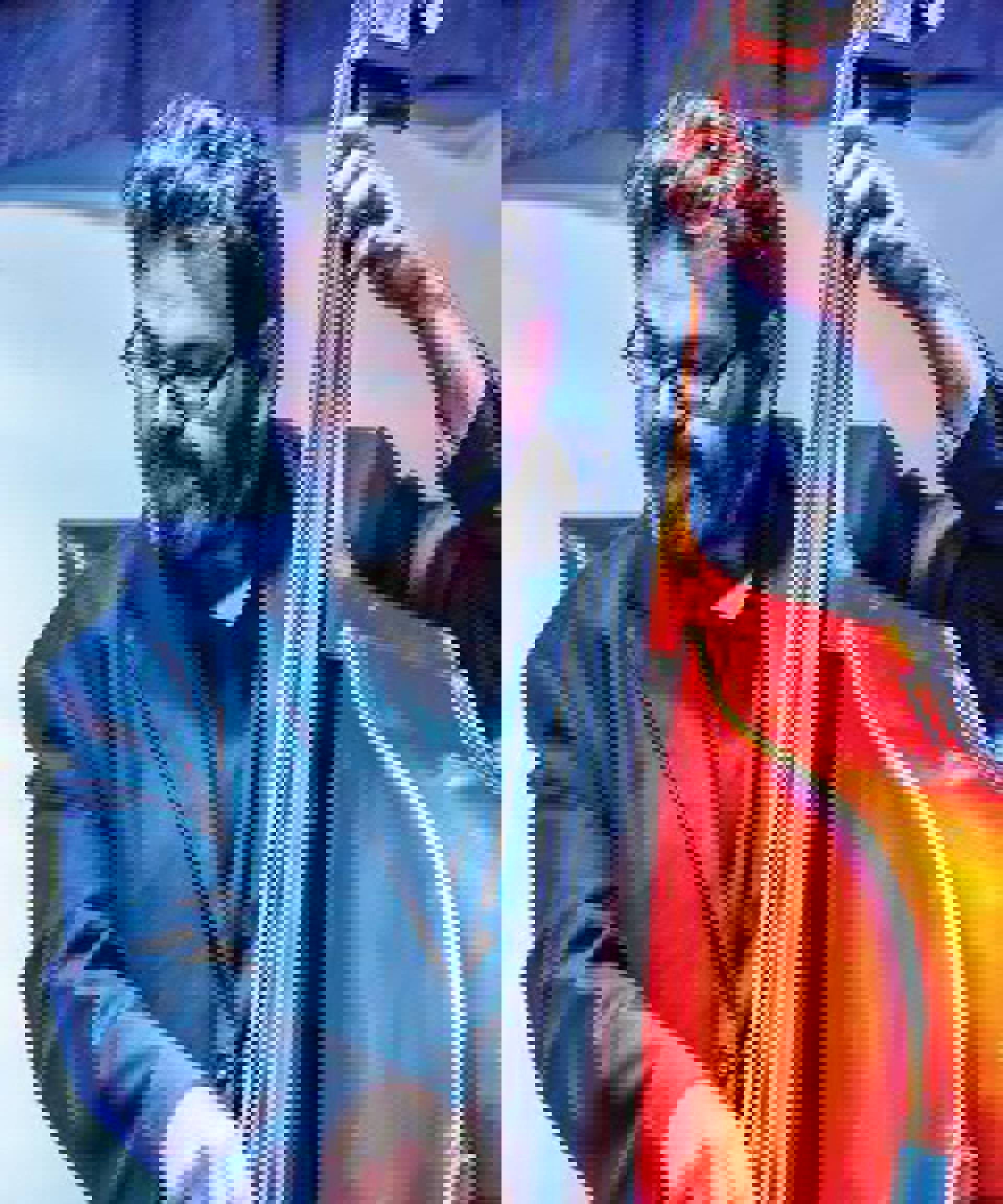 A man playing bass with salt and pepper hair, glasses and a beard