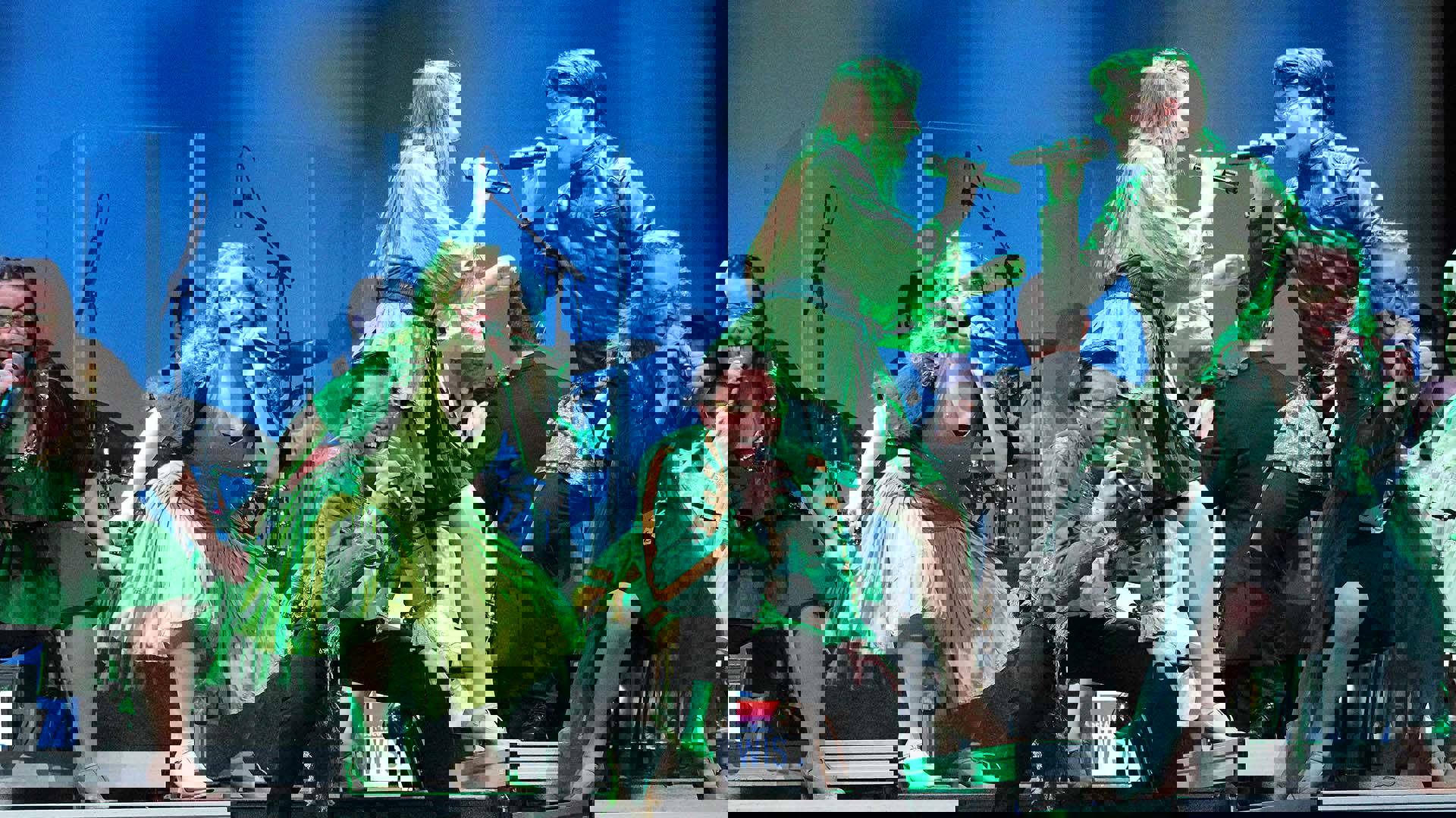 Kids from Wisconsin performing on stage. They are all wearing green and black outfits.