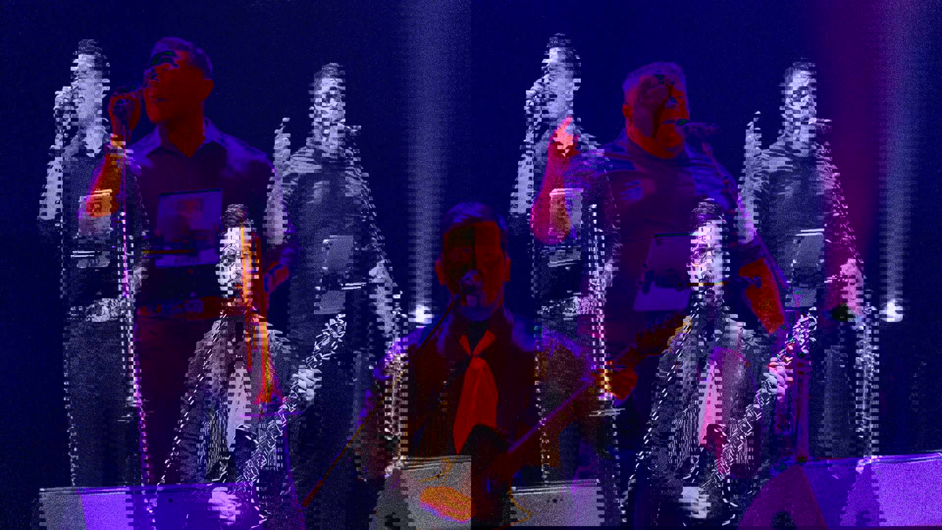 Three men with dark hair and black and white face paint sing into mics and play instruments.