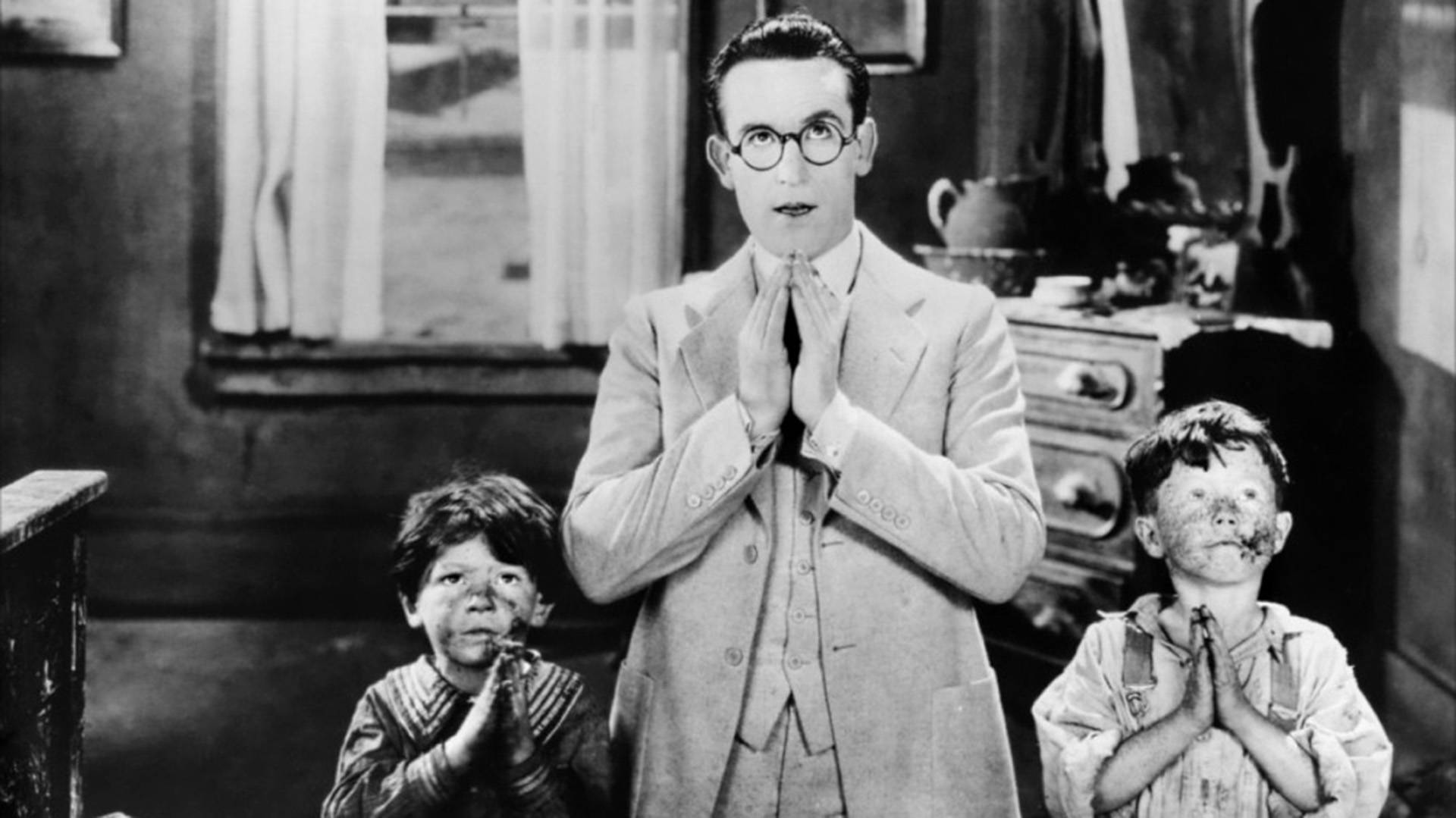 A light complexion man and two children look to the sky and hold their hands in prayer in a scene from "For Heaven's Sake (1926)."