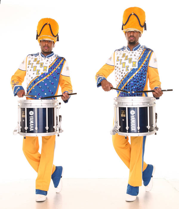 Two Black snare drummers in full yellow uniform and yellow shakos (decorative marching band hats).