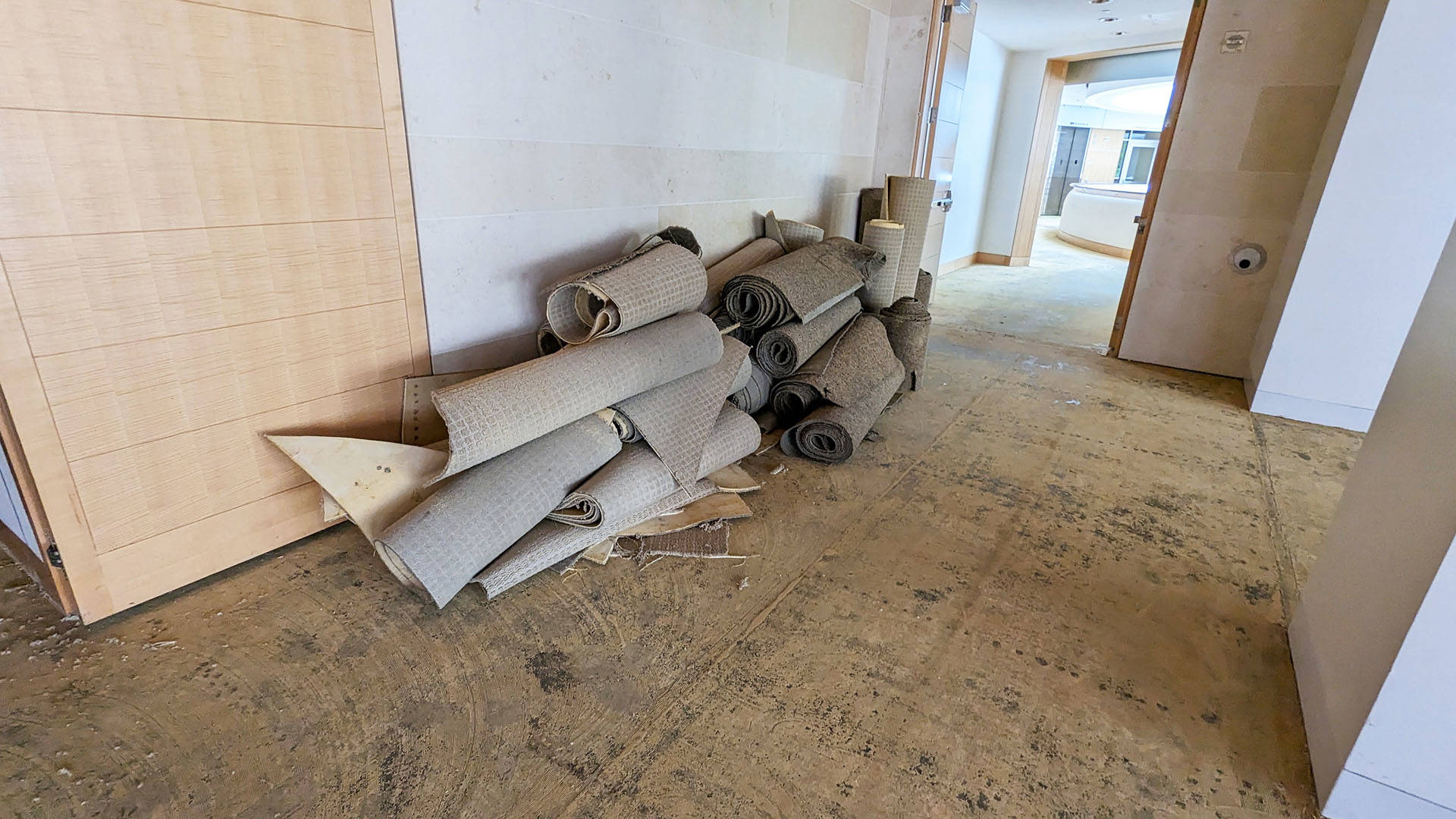 rolled up used carpeting on a tan floor