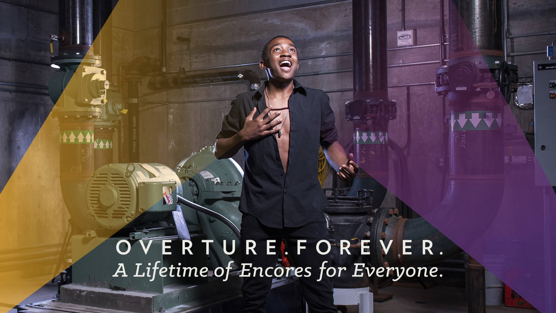 Banner text reads, "Overture. Forever. A Lifetime of Encores for Everyone." A young black man with short hair, a necklace and an open black shirt has an excited look on his face and is standing in an industrial setting with large pipes behind him. There are opaque yellow and purple streaks in the design.