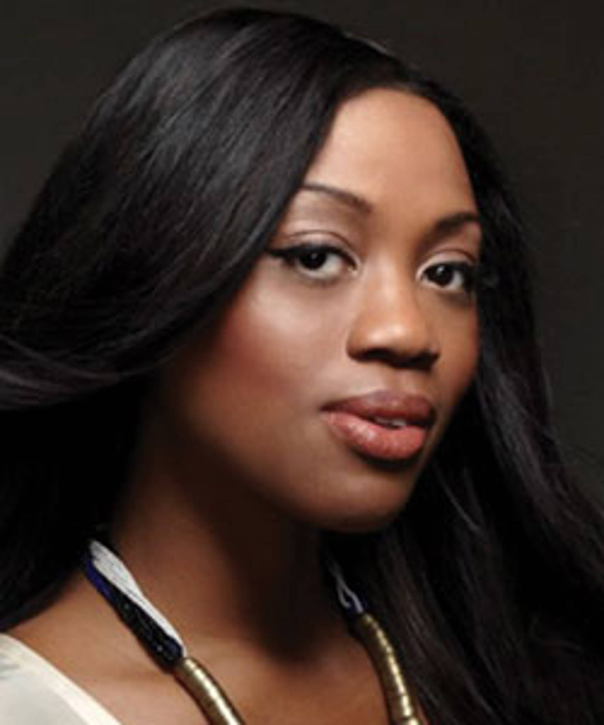 Headshot of an African American woman smiling towards the camera with dark hair and a necklace