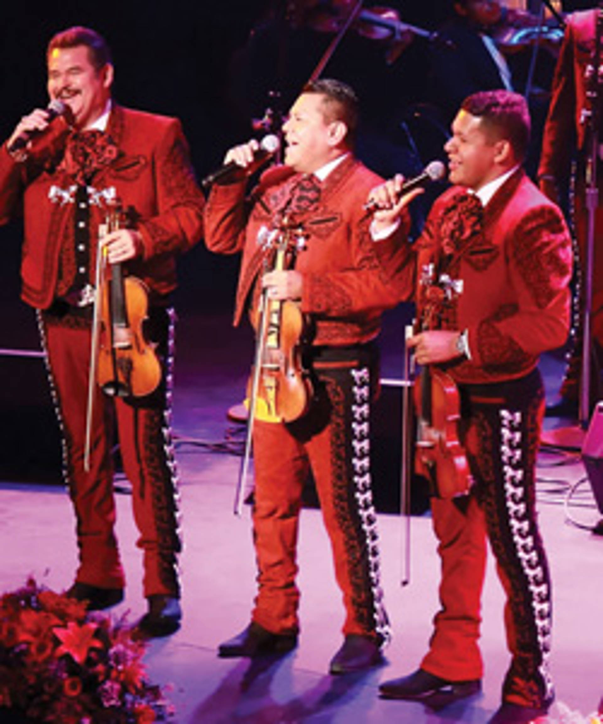 Three men wearing mariachi outfits and holding violins.