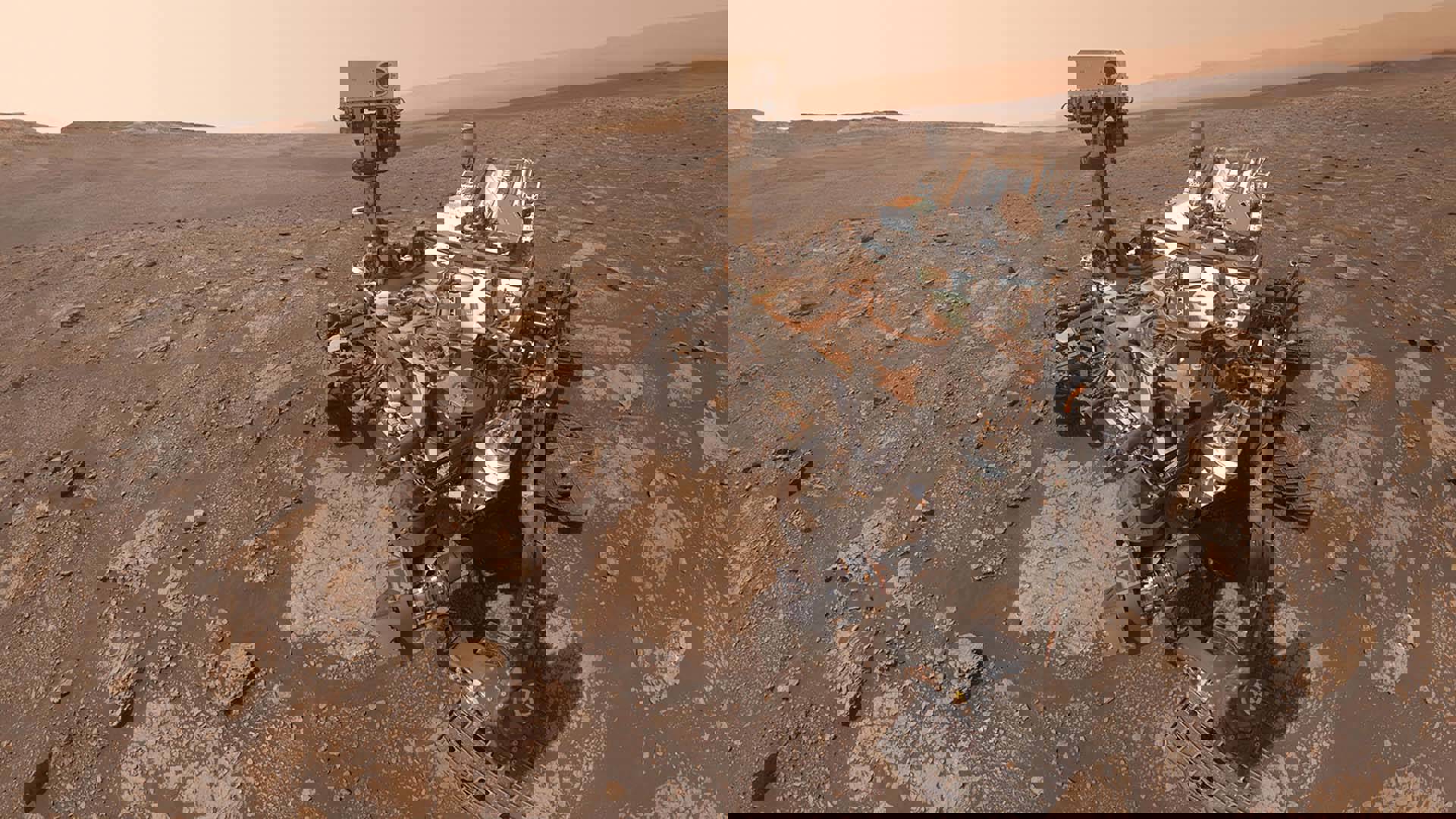 Curiousity, a Mars rover, taking a selfie in a barren and rocky landscape.