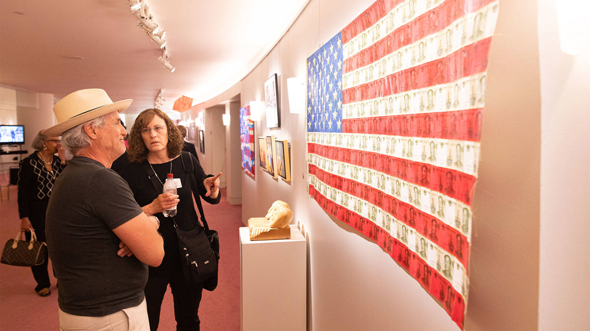 A caucasian man and woman look at a piece of art on a wall